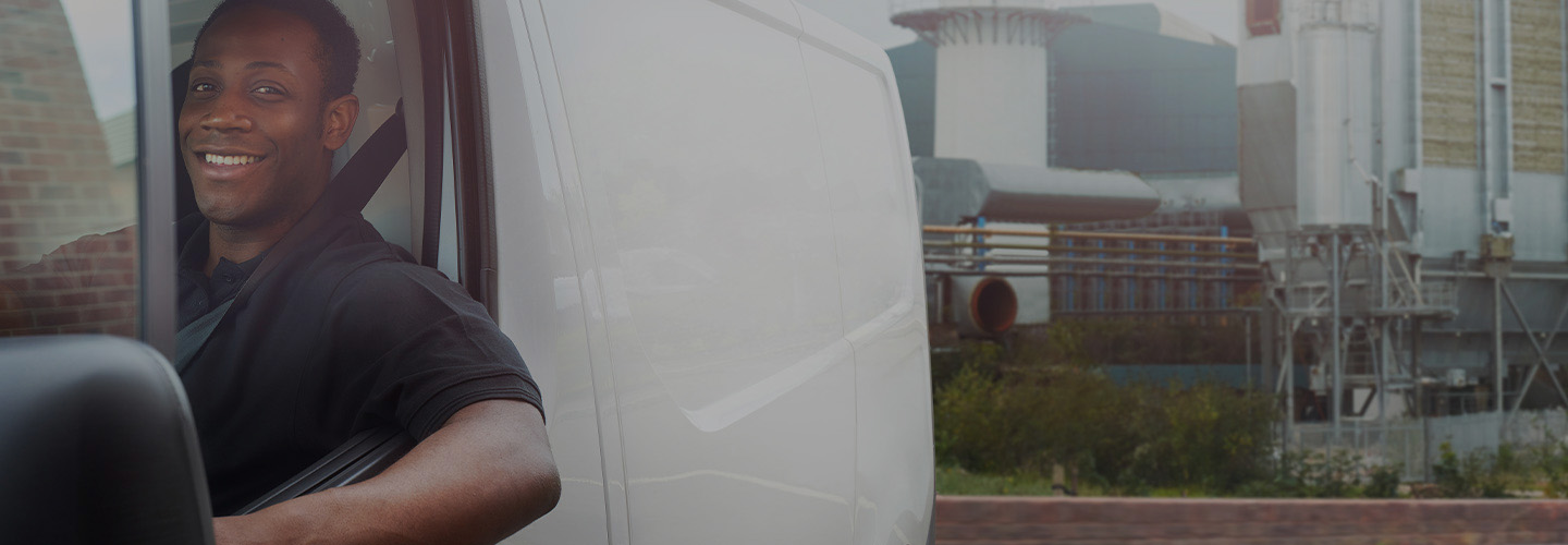 smiling man driving a work van from a factory