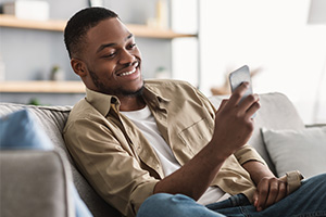 man smiling using his cell phone on a couch