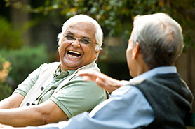 two men laughing while sitting on a bench