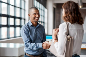 Shot of a young businessman shaking hands with a woman in an office