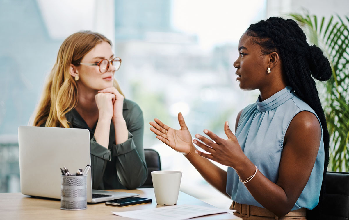 Two diverse businesswomen having a discussion to share ideas and plans while working together in an office