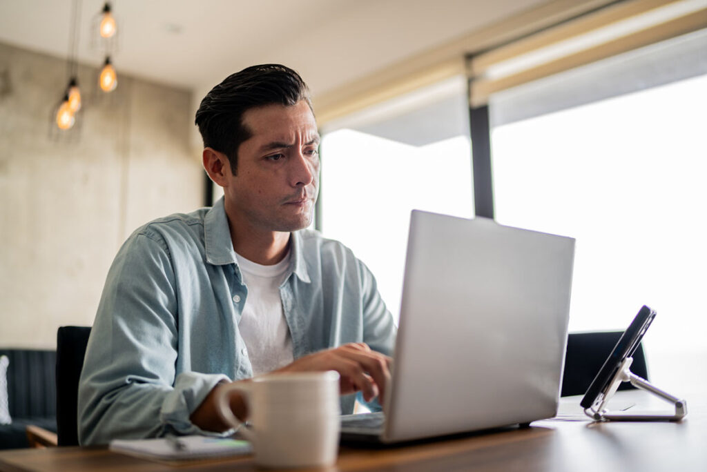 Mid adult man working using laptop at home