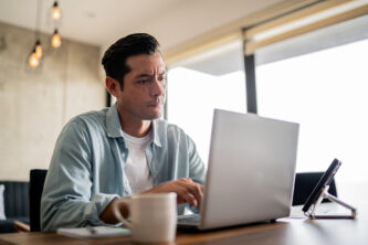 Mid adult man working using laptop at home