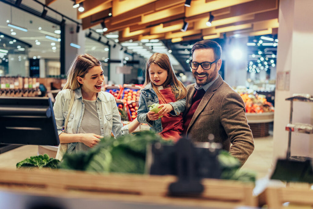Parents and daughter buying vegetables in market