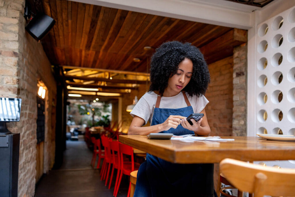 Waitress working at a restaurant doing the accountancy and using the calculator on her cell phone