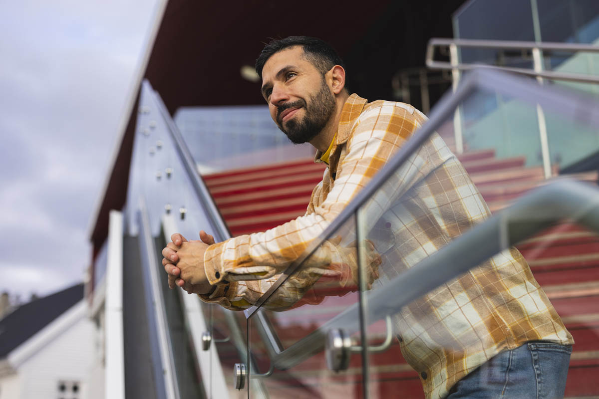 A thoughtful man pauses on a modern city staircase.