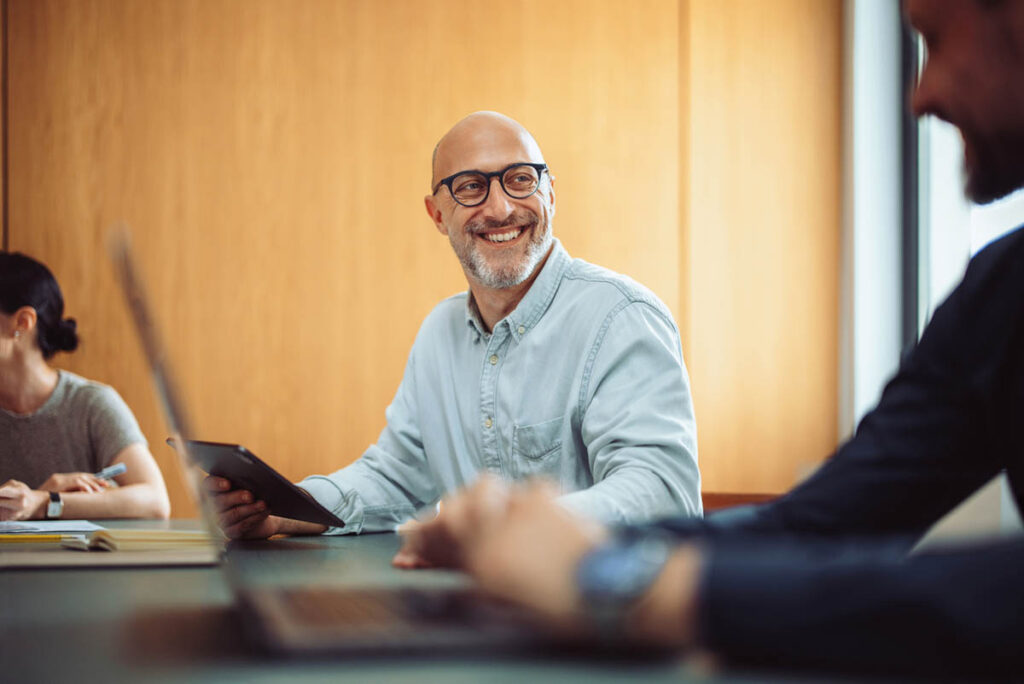 Mature businessman smiling during a meeting with colleagues.