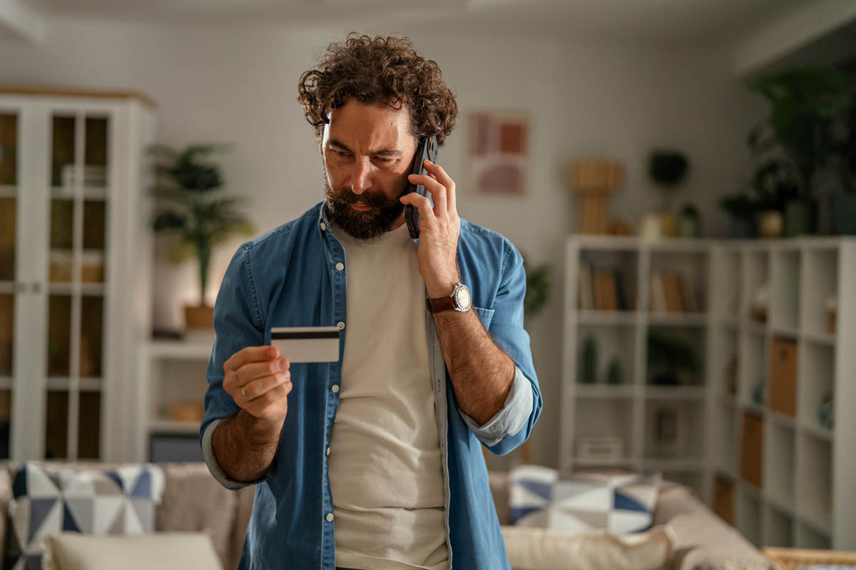 Concerned man making a phone call while holding his credit card