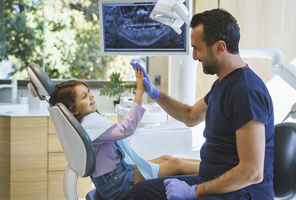 Dentist giving a high five to little girl at dental clinic